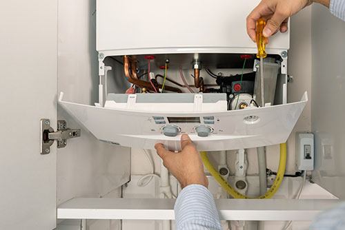HVAC technician repairing an indoor boiler in American Fork