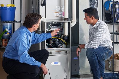 65df8c11f3e4c468cbd351a5_furnace repair vs replacement – Copy HVAC technician explaining furnace repair and maintenance to a homeowner in American Fork, UT